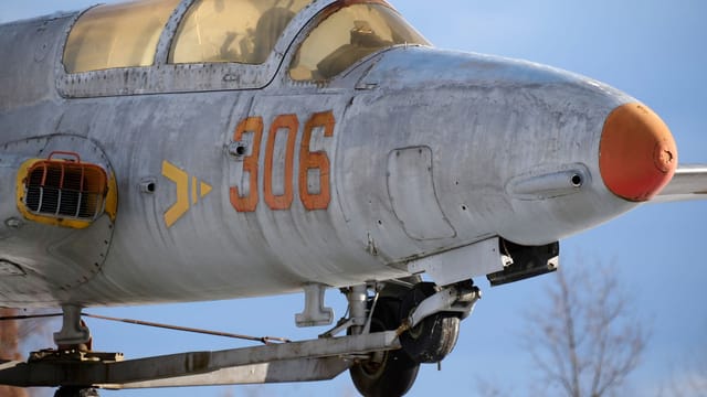 Close-up of a vintage military jet on display outdoors with visible wear and unique number marking.