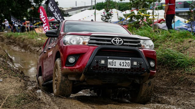 Red SUV navigating muddy off-road terrain during an event in Pasig, Philippines.