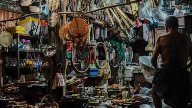 Elderly man browsing a traditional market stall with assorted items in Taizhou, China.