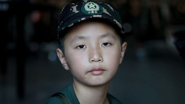Close-up portrait of an Asian boy wearing a military-inspired cap with copyspace.