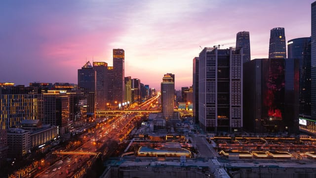 A breathtaking panoramic view of Beijing's urban skyline at dusk with vibrant city lights and a colorful sky.