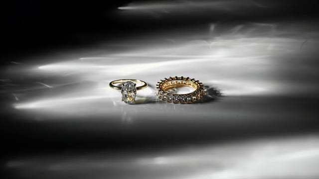 A stunning close-up of elegant gold and diamond rings on a reflective surface.