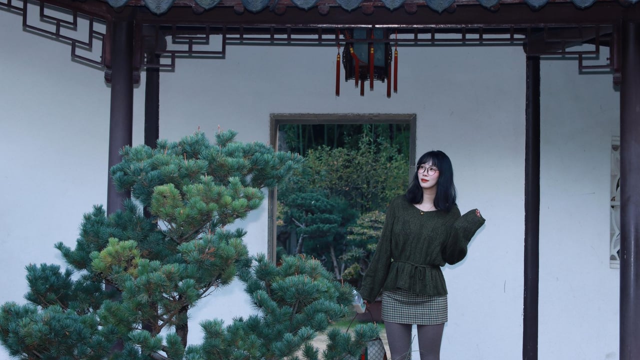 Woman standing in a traditional Chinese garden in Nanjing, China, wearing fashionable clothing.