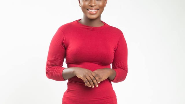 Young woman in a red dress posing confidently with a radiant smile.