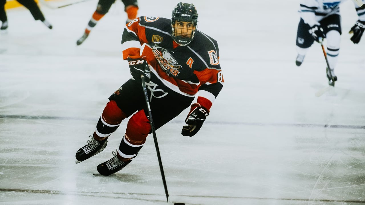 Dynamic action shot of a hockey player skating on an ice rink during a game.