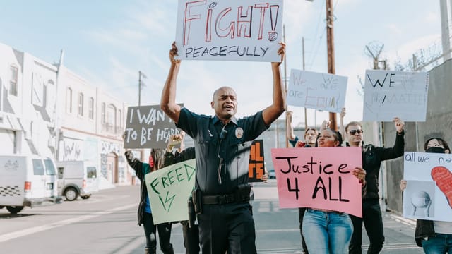 A diverse group peacefully protests for justice and equality, holding signs on a city street.