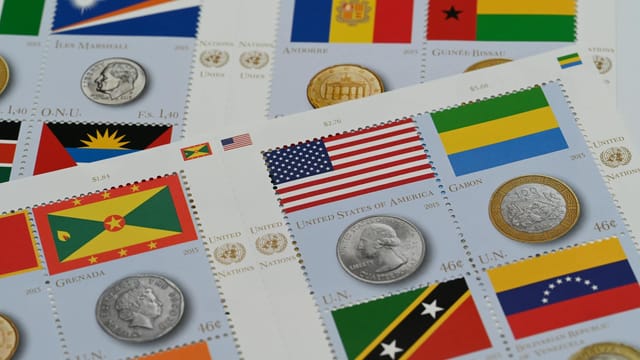 A close-up of international stamps and coins featuring country flags, promoting global culture.