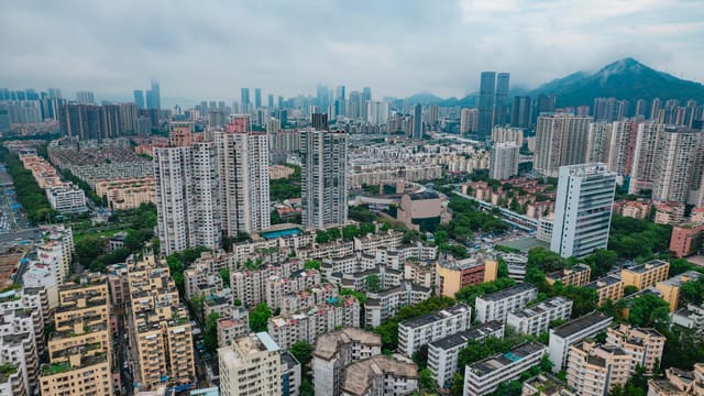Aerial view of Shenzhen's modern skyline in Guangdong, China. Dense urban landscape with skyscrapers and mountains.