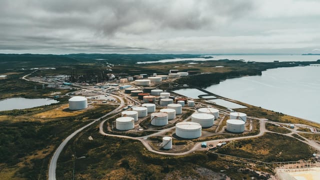 Aerial shot of industrial storage tanks near a waterfront landscape, showcasing industrial infrastructure.