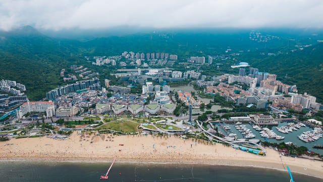 Stunning aerial view of Shenzhen's coastline, showcasing city, beach, and marina.