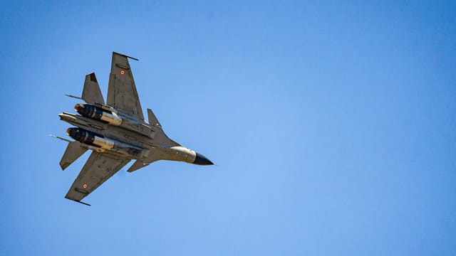 A military fighter jet captured soaring through a clear blue sky, demonstrating aviation prowess.