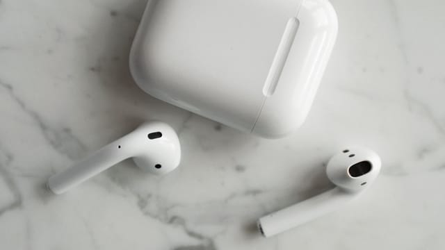 High-quality image of wireless earbuds and charging case on marble surface, showcasing modern technology.