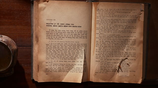 A vintage open book with text in Vietnamese on a wooden table, showcasing old literature.