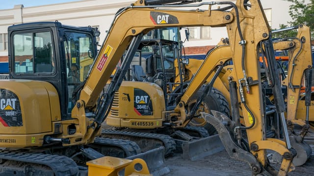 A row of parked excavators at a construction site, ready for heavy duty work.