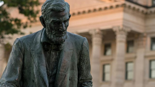 Statue of Abraham Lincoln with a historic architectural backdrop.