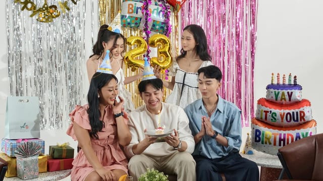 Group of friends celebrating a birthday indoors with gifts and cake in Jakarta.