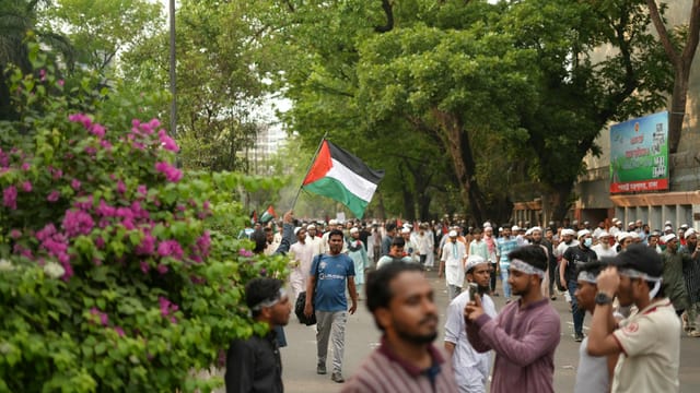 A crowd participates in a pro-Palestine rally in Dhaka, Bangladesh, waving flags in solidarity.