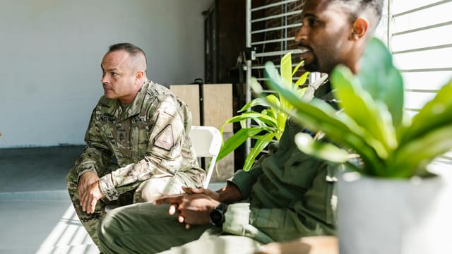 Veterans in uniform participate in a group therapy session indoors.