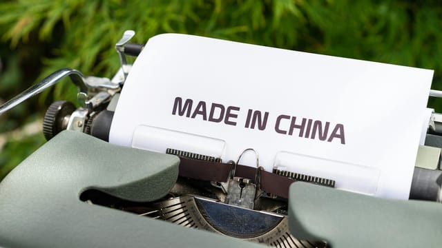 Close-up of a vintage typewriter with 'Made in China' typed, set in an outdoor environment.