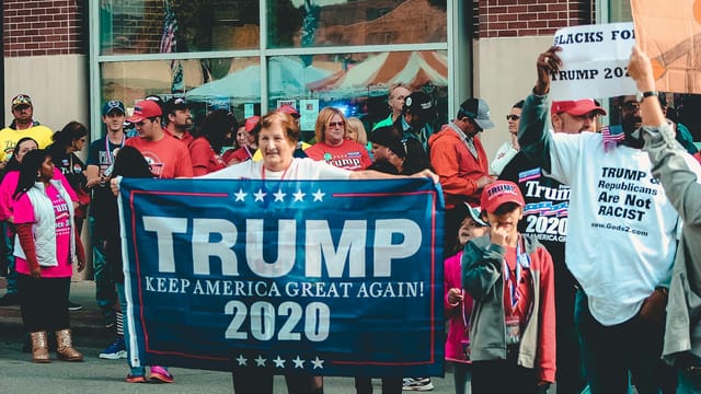 A crowded political rally in Wheeling, showcasing Trump supporters with banners and signs.