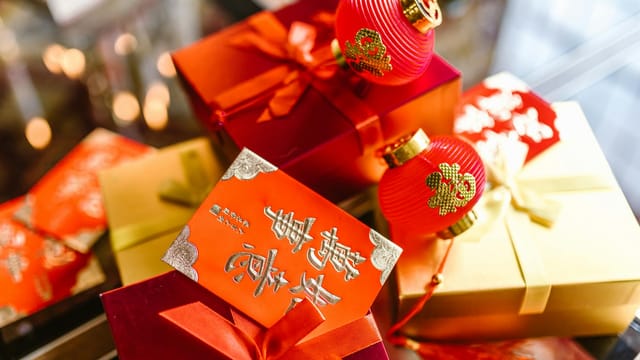 Colorful gift boxes with red packets and lanterns for Chinese New Year celebration.