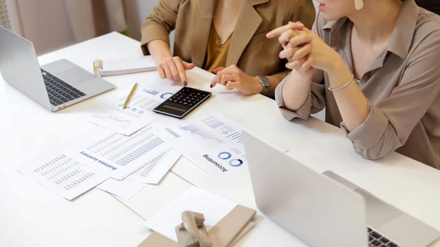 Two professionals collaborating on financial documents in a modern office setting.