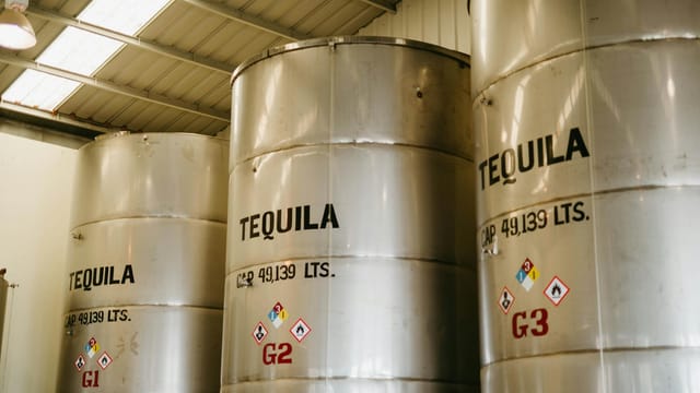 Large tequila storage tanks inside a Mexican distillery with visible capacity markings.