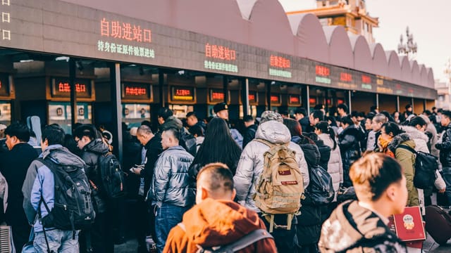 A crowd of people waiting in line at a ticket station in Beijing, China, showcasing modern urban life.
