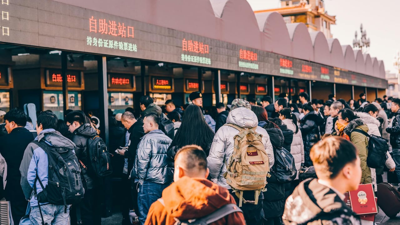 A crowd of people waiting in line at a ticket station in Beijing, China, showcasing modern urban life.