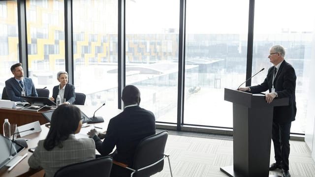 Corporate professionals engaged in a formal business meeting in a modern conference room setting.