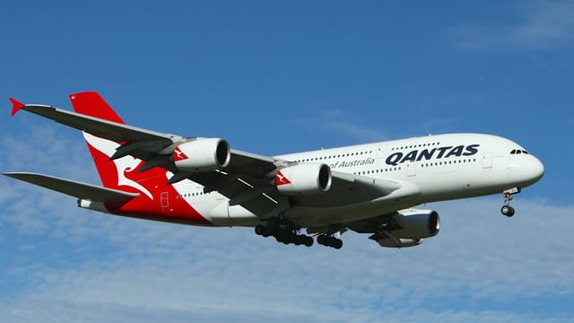 Qantas Airbus A380 soaring against a clear blue sky, showcasing aviation excellence.
