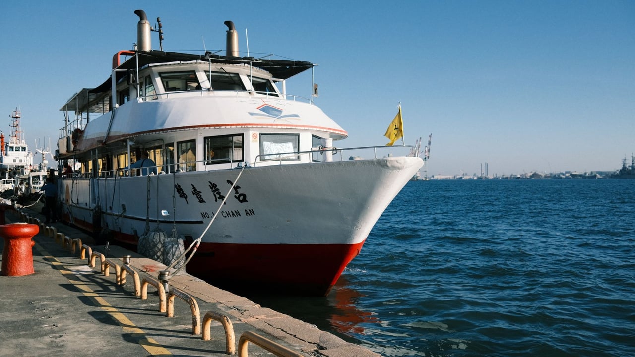 A passenger ferry docked at Kaohsiung Harbor, Taiwan, under a clear blue sky.