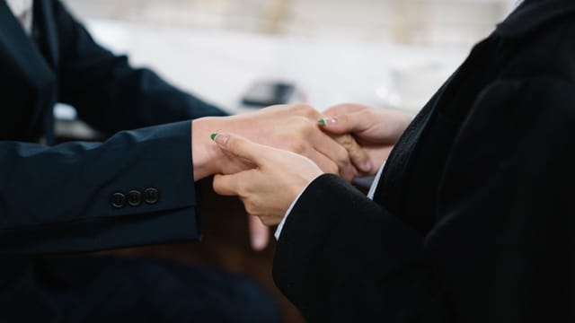 Close-up of two individuals in suits shaking hands, symbolizing business cooperation.