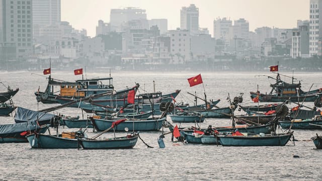 A serene scene of traditional fishing boats with Vietnamese flags in Da Nang harbor.