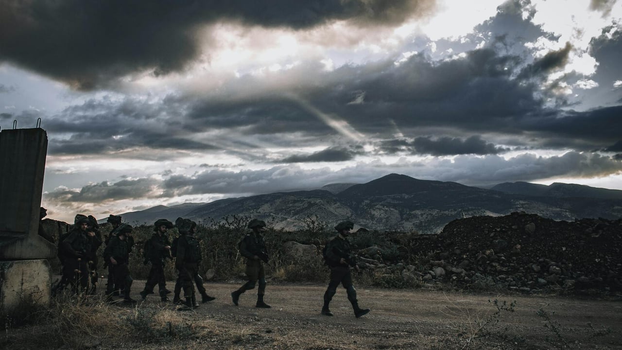 A group of soldiers march through a rugged landscape under a threatening sky in Israel.