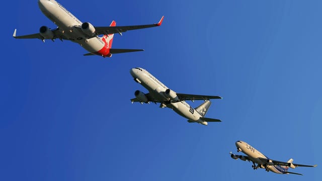 Three commercial airplanes soaring through a clear blue sky, highlighting aviation technology.