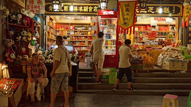 Busy night market with people and colorful products, showcasing Asian culture.
