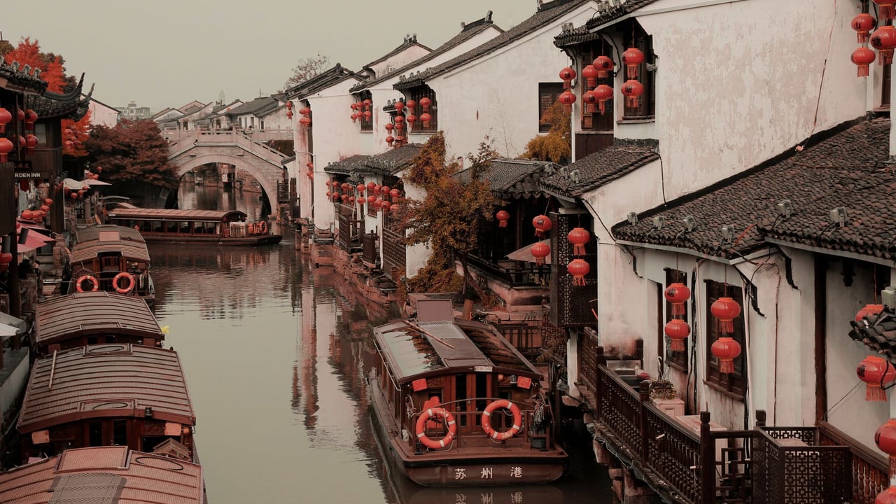 Beautiful canal in Suzhou, China, adorned with red lanterns and traditional boats, showcasing serene reflections.
