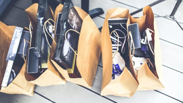 Aerial view of brown paper bags filled with various shopping goods on a wooden floor.