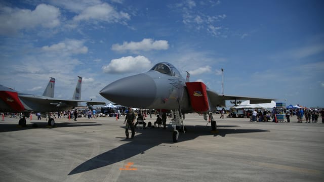 F-15 fighter jet on display at an airshow in Hampton, Virginia, with a crowd in the background.