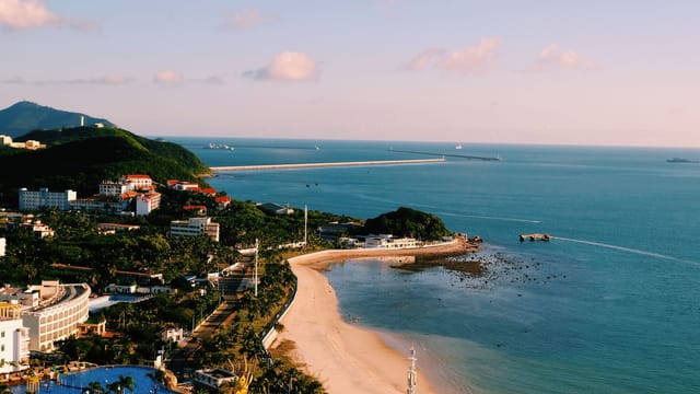 Aerial view of a vibrant coastal cityscape with beach and sea under a bright blue sky.
