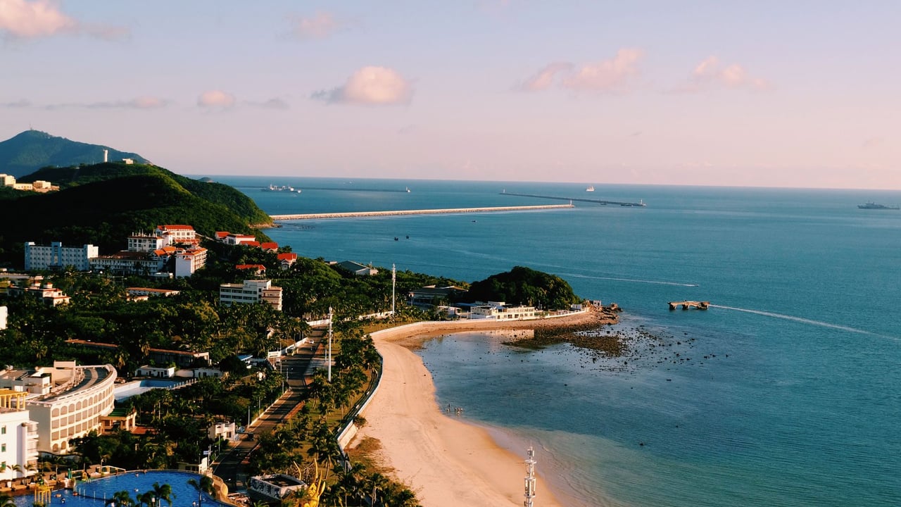 Aerial view of a vibrant coastal cityscape with beach and sea under a bright blue sky.