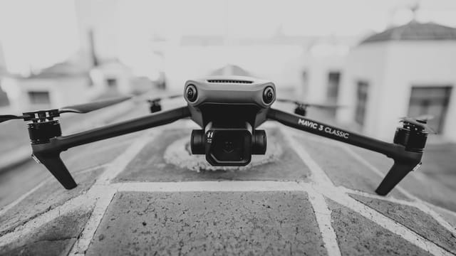 Monochrome image of a Mavic 3 Classic drone positioned on a rooftop, captured up close.