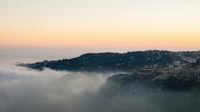 A captivating view of fog-covered mountains in Faraya, Lebanon, at sunset.