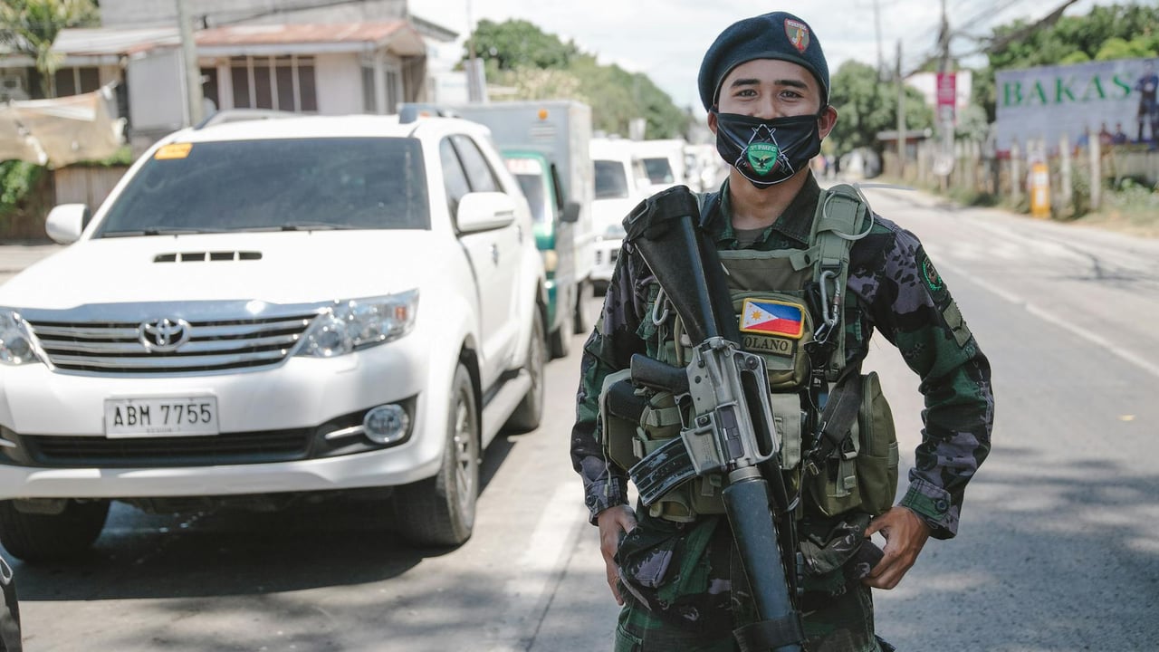 A Philippine soldier in uniform and mask standing on a city street, showcasing military presence.