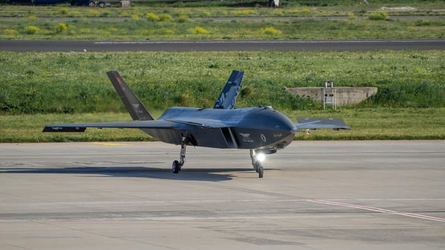 Turkish Baykar Bayraktar Kizilelma drone on a tarmac in Istanbul with aircraft in the background.