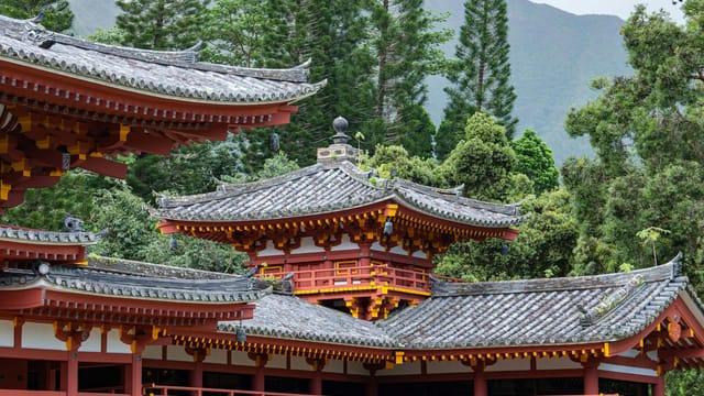 Serene view of a traditional pagoda surrounded by lush trees and mountains.