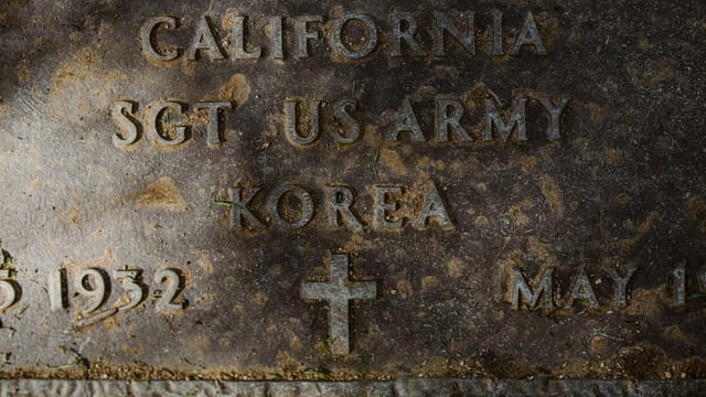 Close-up view of a gravestone commemorating a US Army veteran from the Korean War, featuring engraved text.