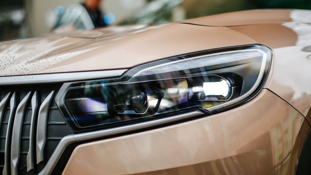 Detailed close-up of a sleek brown electric SUV headlight with stylish design.