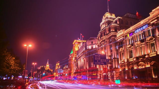 A stunning urban cityscape at night capturing vibrant light trails along an illuminated street.